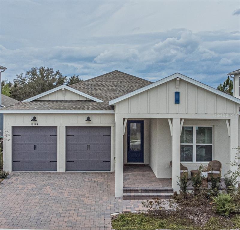 A single-story house with a two-car garage, a covered front porch, and light-colored siding — 13184 DENDY WAY, WINTER GARDEN, FL