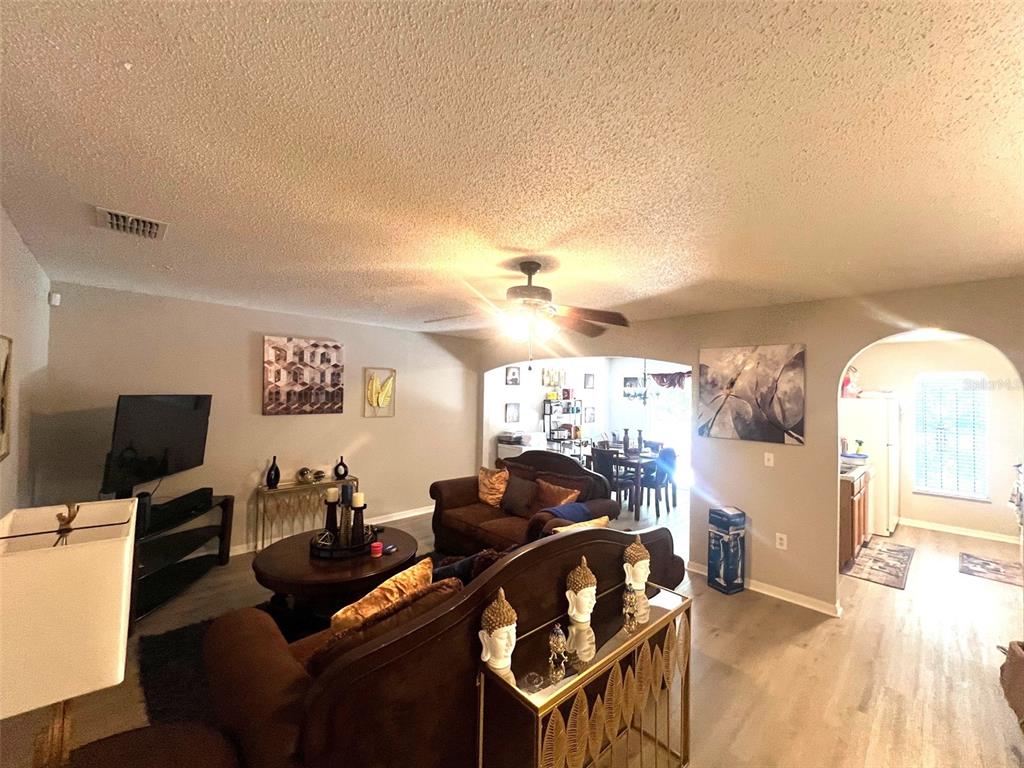 A living room with brown sofas, a coffee table, and an arched entryway to a kitchen — 4617 ASHBURN SQUARE DRIVE, TAMPA, FL