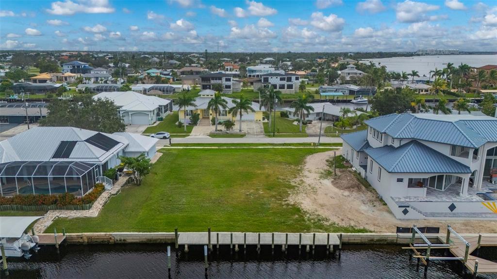 An aerial view shows a vacant waterfront lot situated between two large residential houses — 234 BEENEY ROAD SE, PORT CHARLOTTE, FL