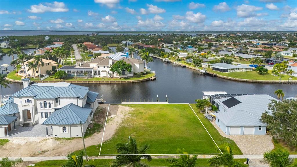An aerial view of a vacant waterfront lot situated between two large residential houses — 234 BEENEY ROAD SE, PORT CHARLOTTE, FL