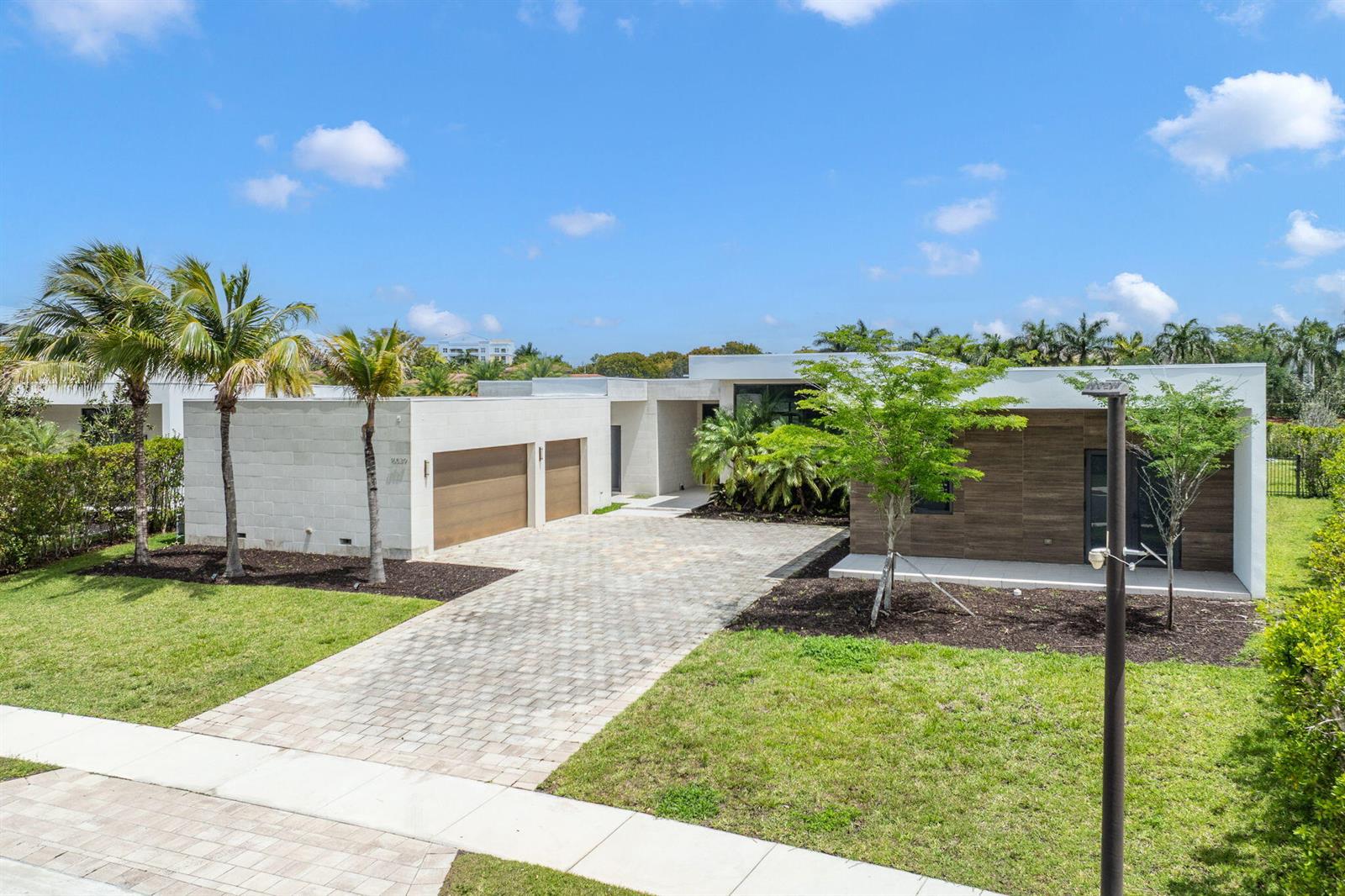 A modern single-story house with a paved driveway, two-car garage, and landscaped front yard — 16539 N Botaniko Dr Drive N, Weston FL 33326, WESTON, FL