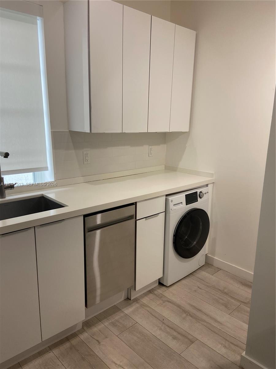 A laundry room features white cabinets, a stainless steel dishwasher, and a front-load washer — 1610 Euclid Ave # A105, Miami Beach FL 33139, MIAMI BEACH, FL