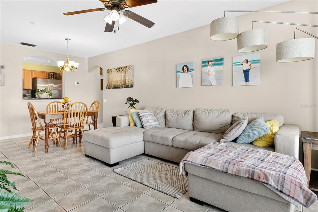 A living room with a gray sectional sofa, tiled floors, and a dining area nearby — 3930 SOUTHPOINTE DRIVE UNIT 214, ORLANDO, FL