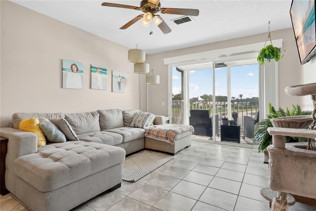 A living room features a large gray sectional sofa, tile flooring, and sliding glass doors — 3930 SOUTHPOINTE DRIVE UNIT 214, ORLANDO, FL