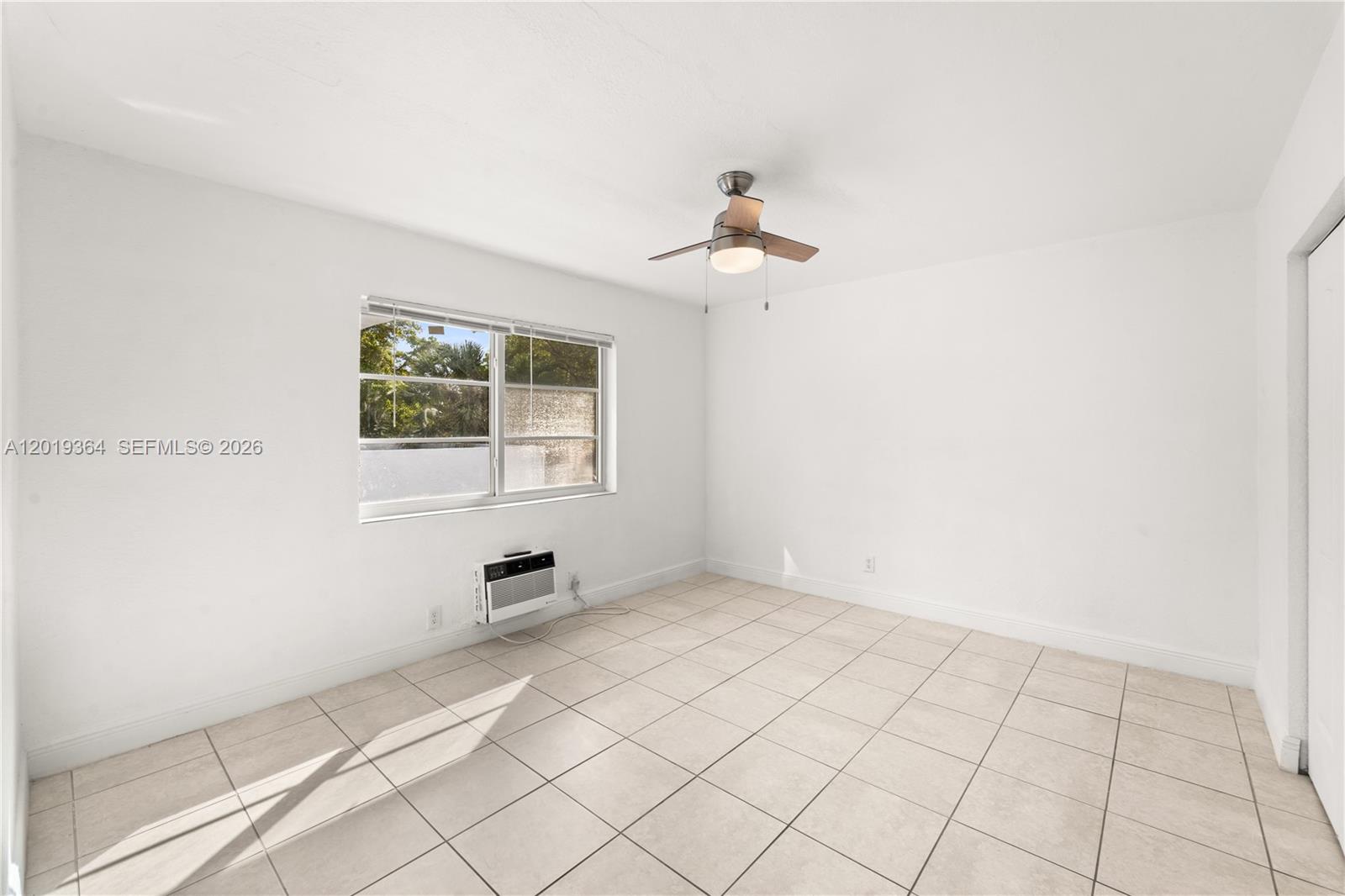 A bedroom with white walls, light-colored tile flooring, a ceiling fan, and a window unit — 6905 Rue Vendome # 8, Miami Beach FL 33141, MIAMI BEACH, FL