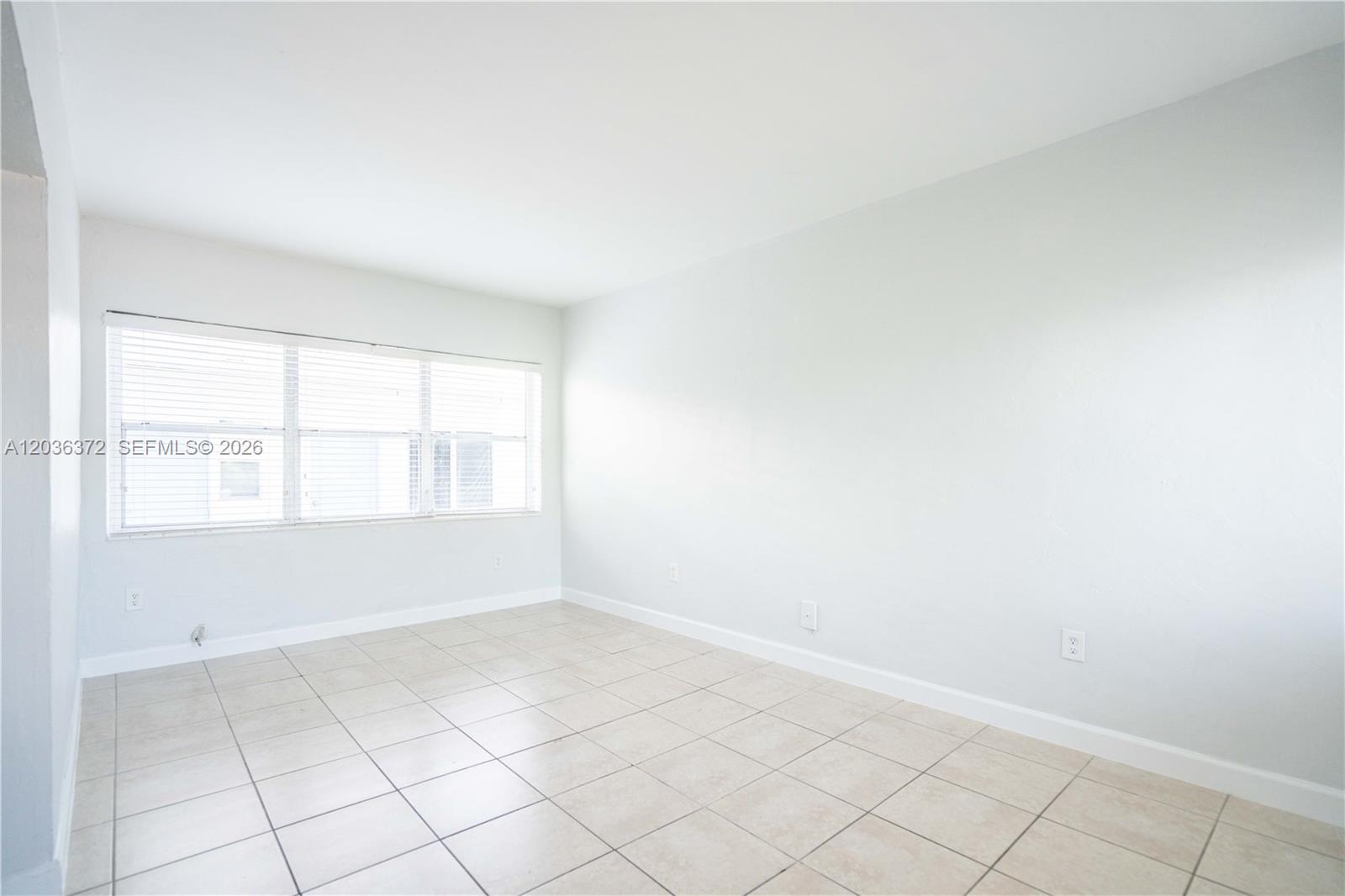 This room features light-colored tile flooring, a window with blinds, and a small kitchenette — 8315 Byron Ave # 7A, Miami Beach FL 33141, MIAMI BEACH, FL