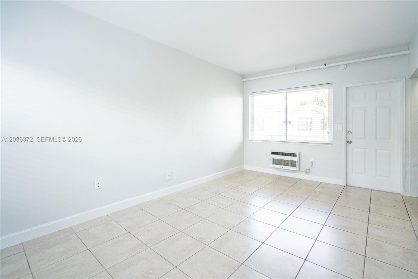 A small kitchenette features dark wood cabinets, a white refrigerator, and a granite countertop — 8315 Byron Ave # 7A, Miami Beach FL 33141, MIAMI BEACH, FL