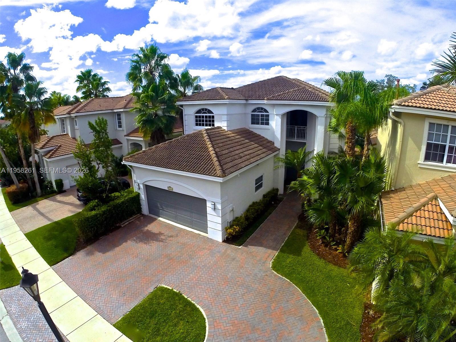 An aerial view of a two-story white house with a tiled roof and brick driveway — 1675 NE 196th St, Miami FL 33179, MIAMI, FL