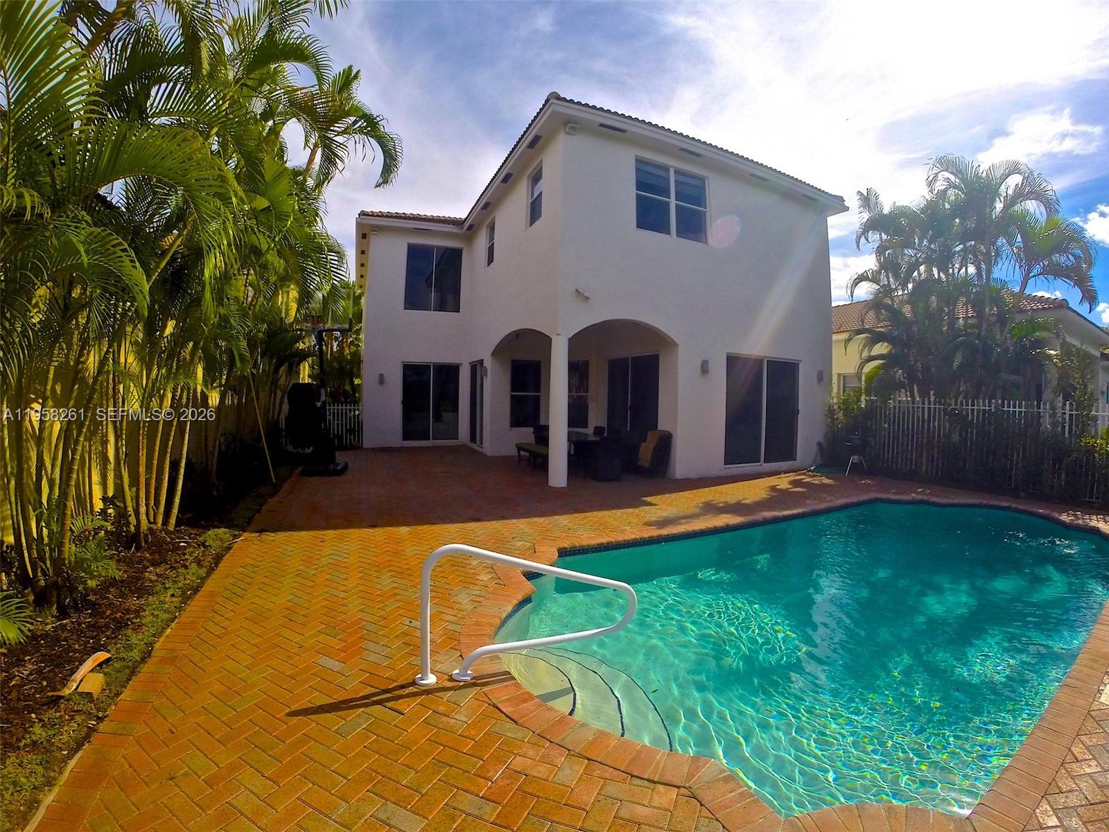 A two-story white house features a backyard swimming pool with a brick paver patio — 1675 NE 196th St, Miami FL 33179, MIAMI, FL