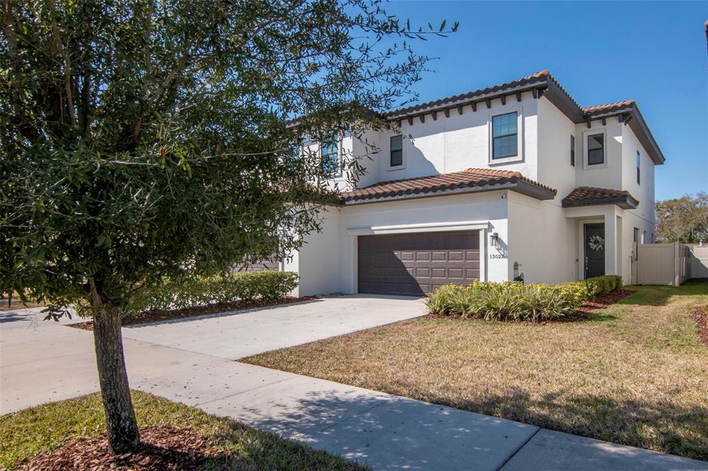 A two-story white stucco house with a brown tile roof and a two-car garage — 13022 SANCTUARY VILLAGE LANE, TAMPA, FL