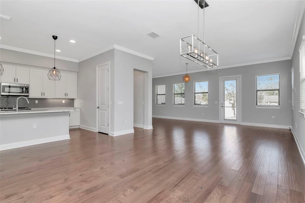 An open-concept kitchen and living area with gray walls, white cabinetry, and wood flooring — 13022 SANCTUARY VILLAGE LANE, TAMPA, FL