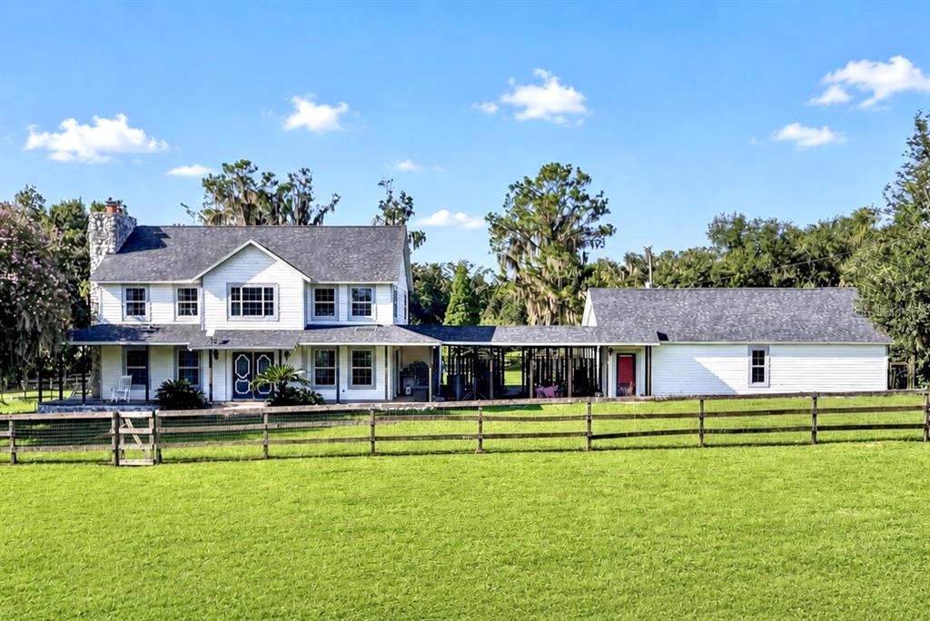A two-story white farmhouse with a stone chimney and a detached garage connected by breezeway — 8922 PRITCHER ROAD, LITHIA, FL
