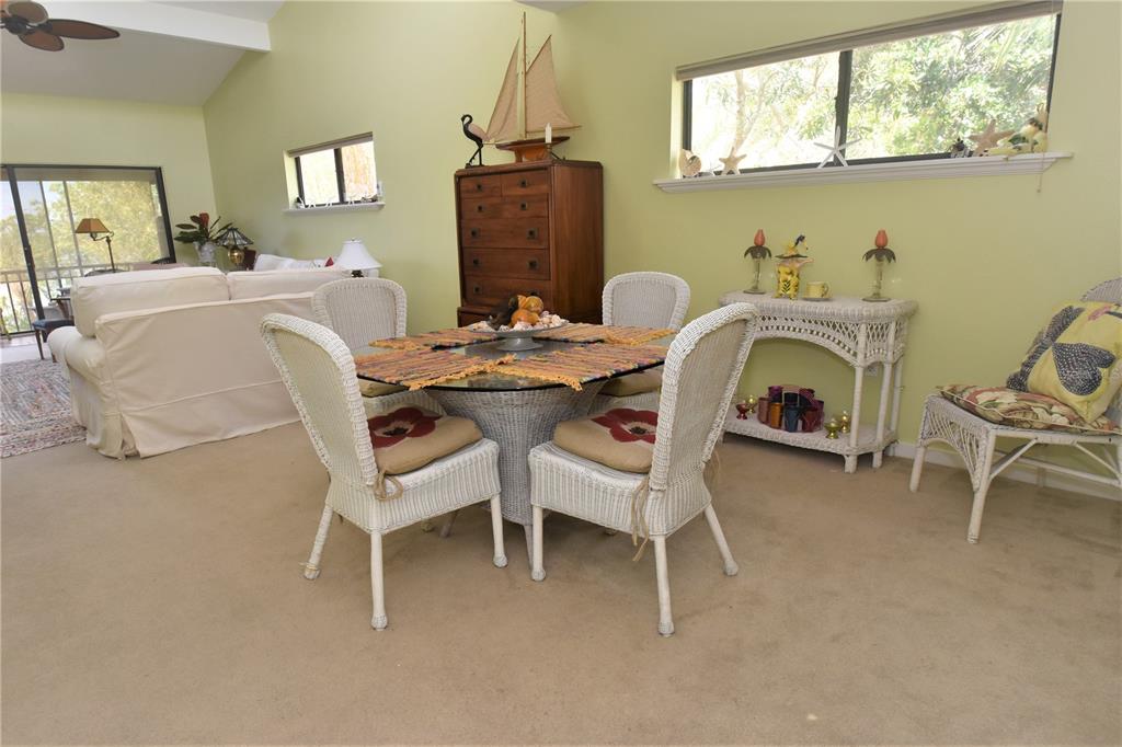 A dining area with a glass-topped wicker table and chairs sits on beige carpet — 1617 BAYHOUSE COURT UNIT BA221, SARASOTA, FL