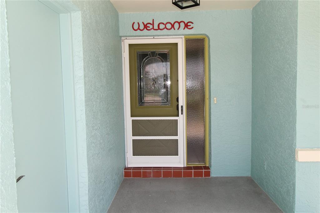 A front entryway features a light blue wall, a screen door, and a sidelight window — 309 BRYCE COURT, SUN CITY CENTER, FL