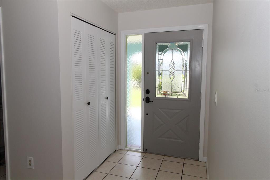 An entryway features a gray front door with a glass insert, a sidelight, and white closet doors — 309 BRYCE COURT, SUN CITY CENTER, FL
