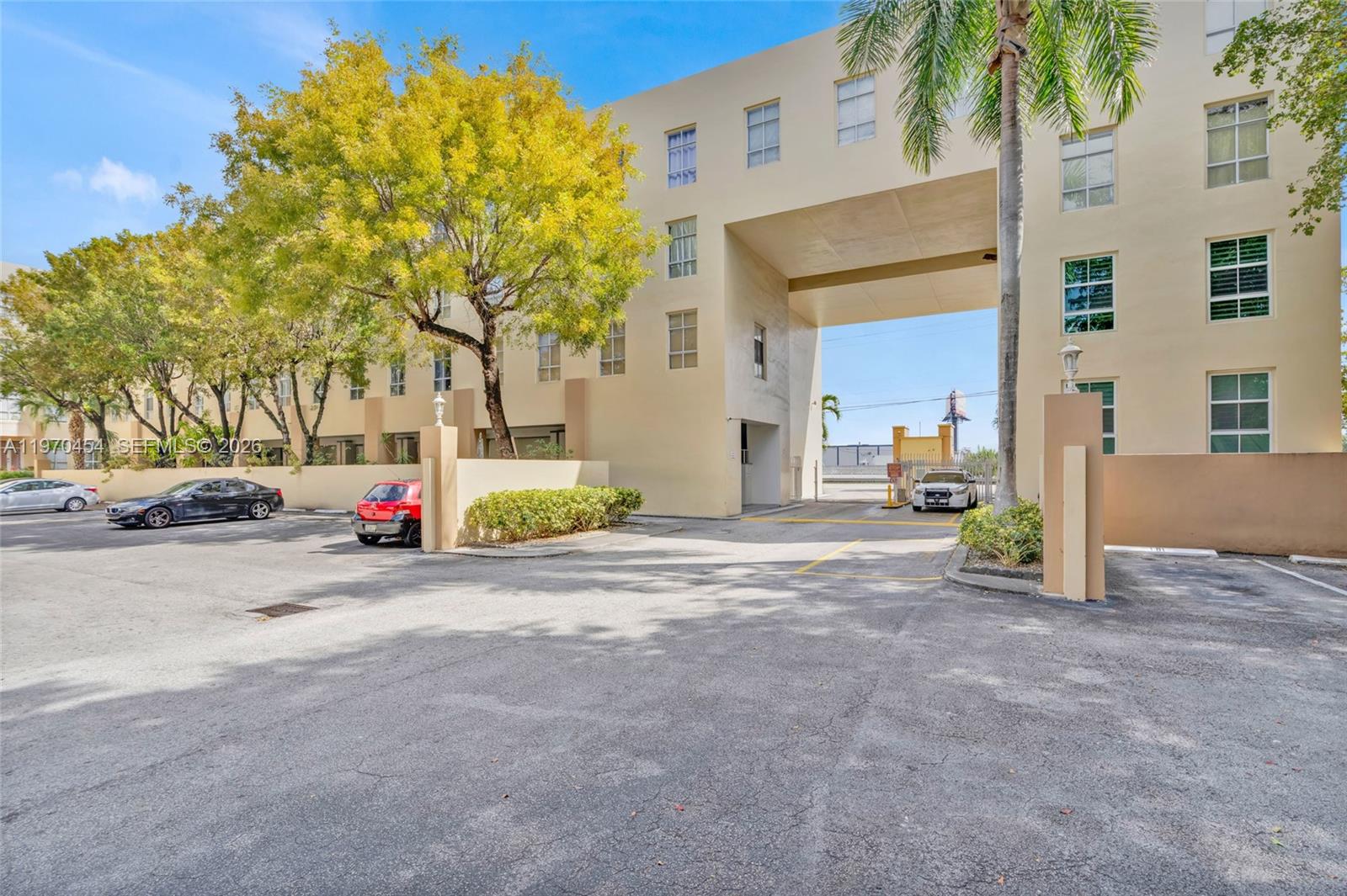 The exterior of a multi-story apartment building features a parking lot and a gated entrance — 7400 W 20th Ave # 402, Hialeah FL 33016, HIALEAH, FL