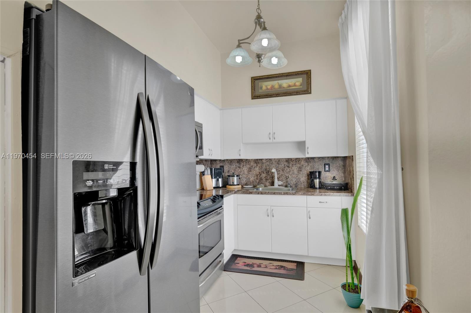 A kitchen features white cabinets, stainless steel appliances, and a brown granite countertop — 7400 W 20th Ave # 402, Hialeah FL 33016, HIALEAH, FL