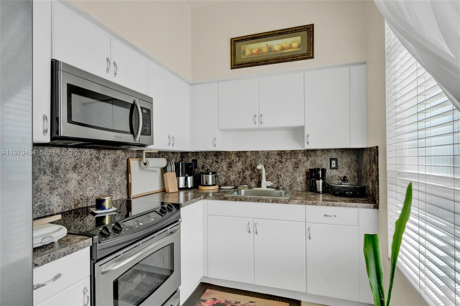 A kitchen features white cabinets, a stainless steel microwave and stove, and brown countertops — 7400 W 20th Ave # 402, Hialeah FL 33016, HIALEAH, FL
