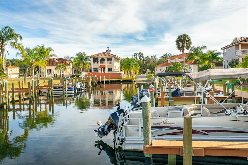A canal with multiple boat slips and docked pontoon boats in front of residential buildings — 10228 W MIDDLEBURG LOOP, HOMOSASSA, FL