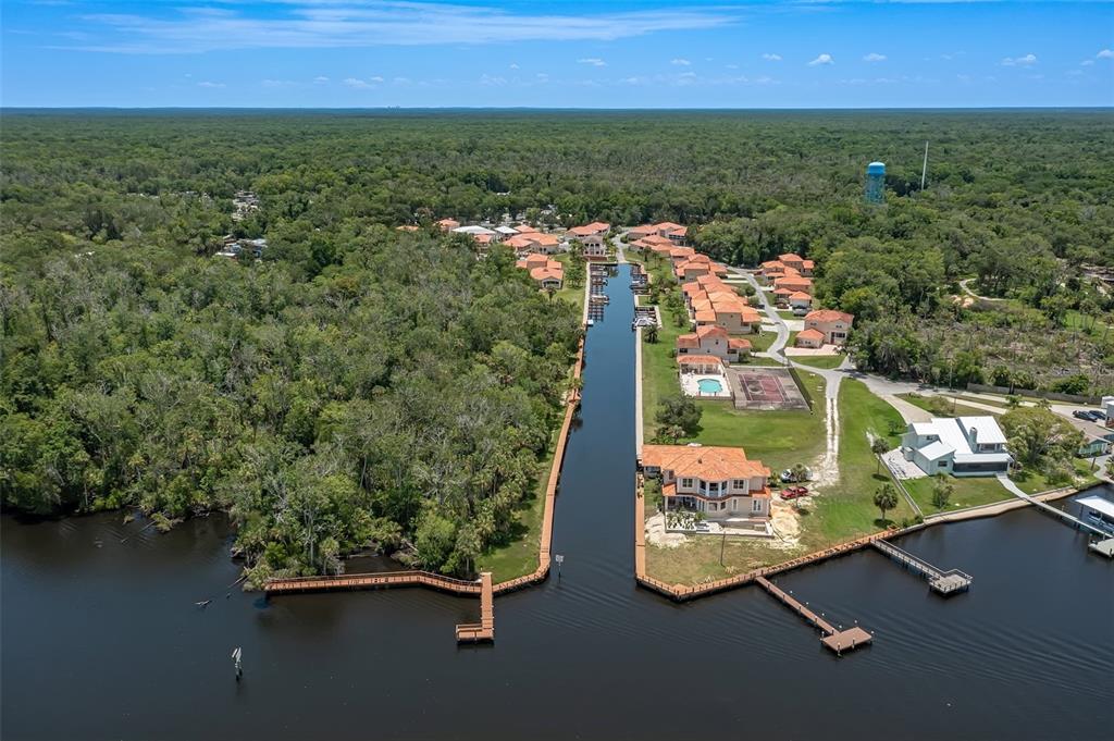 An aerial view shows a canal leading to a residential community surrounded by dense forest — 10228 W MIDDLEBURG LOOP, HOMOSASSA, FL