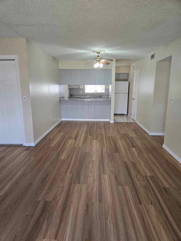 A living area with wood-look flooring leads to a kitchen with a breakfast bar — 1000 LAKE OF THE WOODS BOULEVARD UNIT 201E, CASSELBERRY, FL