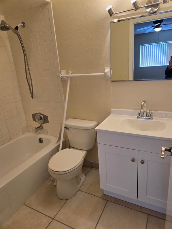 A bathroom features a white vanity, a toilet, and a shower-tub combination with tiled walls — 1000 LAKE OF THE WOODS BOULEVARD UNIT 201E, CASSELBERRY, FL