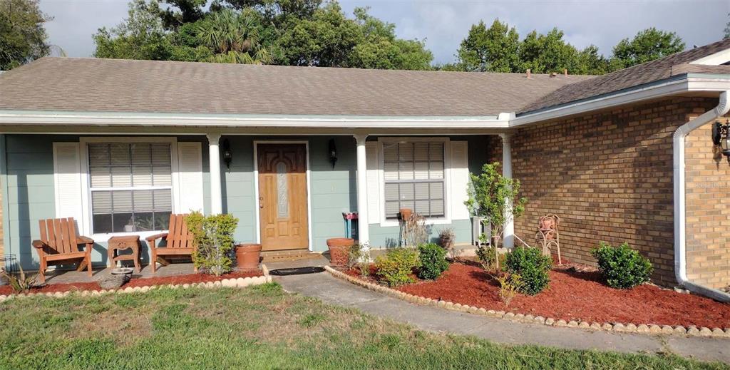 A single-story house features a brick and light-green exterior with a front porch and walkway — 2091 OLDHAM AVENUE, DELTONA, FL