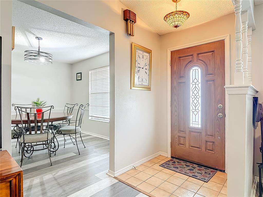 An entryway with a tiled floor and wooden door leads into a dining room area — 2091 OLDHAM AVENUE, DELTONA, FL