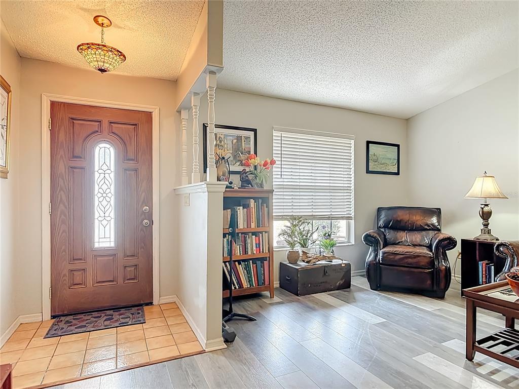 An entryway with a tile floor leads into a living area featuring wood-look flooring — 2091 OLDHAM AVENUE, DELTONA, FL