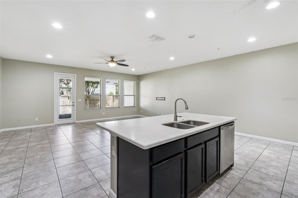 A kitchen island with a sink sits in an open-concept room with tile flooring — 618 MERRY BROOK CIRCLE, SANFORD, FL