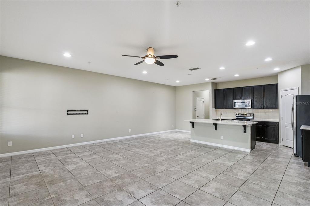 An open-concept living area features tile flooring, a ceiling fan, and a kitchen with dark cabinets — 618 MERRY BROOK CIRCLE, SANFORD, FL
