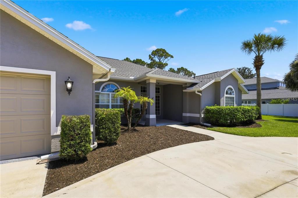 A single-story house with a garage and illuminated landscaping at night — 62 SENTINEL TRAIL, PALM COAST, FL