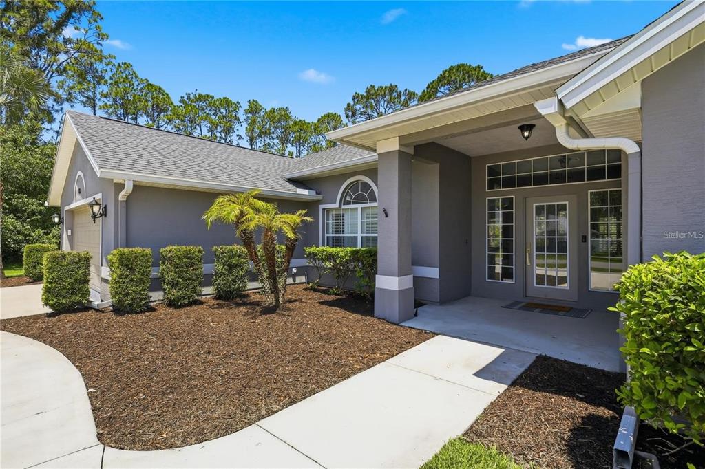 A gray single-story house features a concrete driveway, a garage, and manicured landscaping — 62 SENTINEL TRAIL, PALM COAST, FL