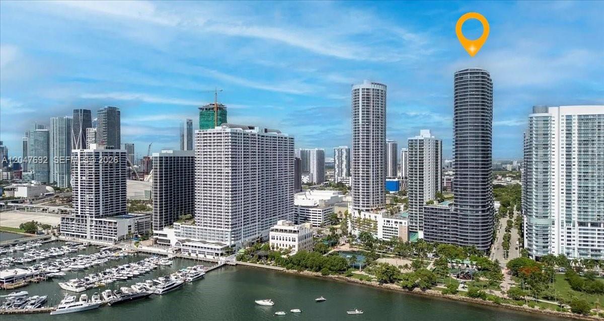 An aerial view of a Miami waterfront skyline featuring a prominent cylindrical residential skyscraper — 488 NE 18th St # 1806, Miami FL 33132, MIAMI, FL