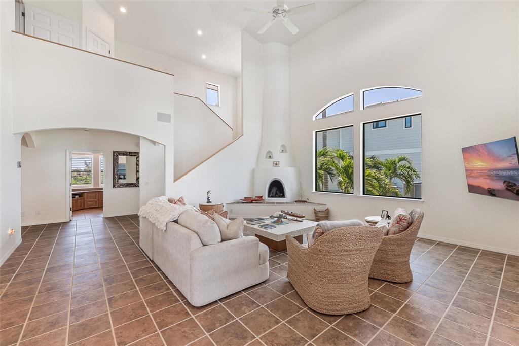 A living room features a high ceiling, a white fireplace, tile floors, and large windows — 16776 GRANDE QUAY DRIVE, BOCA GRANDE, FL