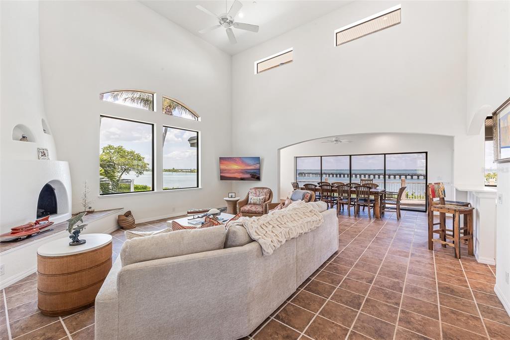 A spacious living room with a fireplace, high ceilings, tile floors, and waterfront views — 16776 GRANDE QUAY DRIVE, BOCA GRANDE, FL
