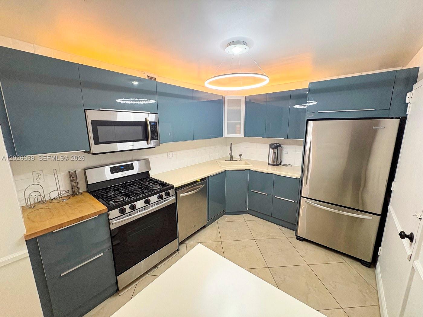 A kitchen features blue glossy cabinets, stainless steel appliances, and a circular ceiling light — 2030 S Ocean Dr # 723, Hallandale Beach FL 33009, HALLANDALE BEACH, FL