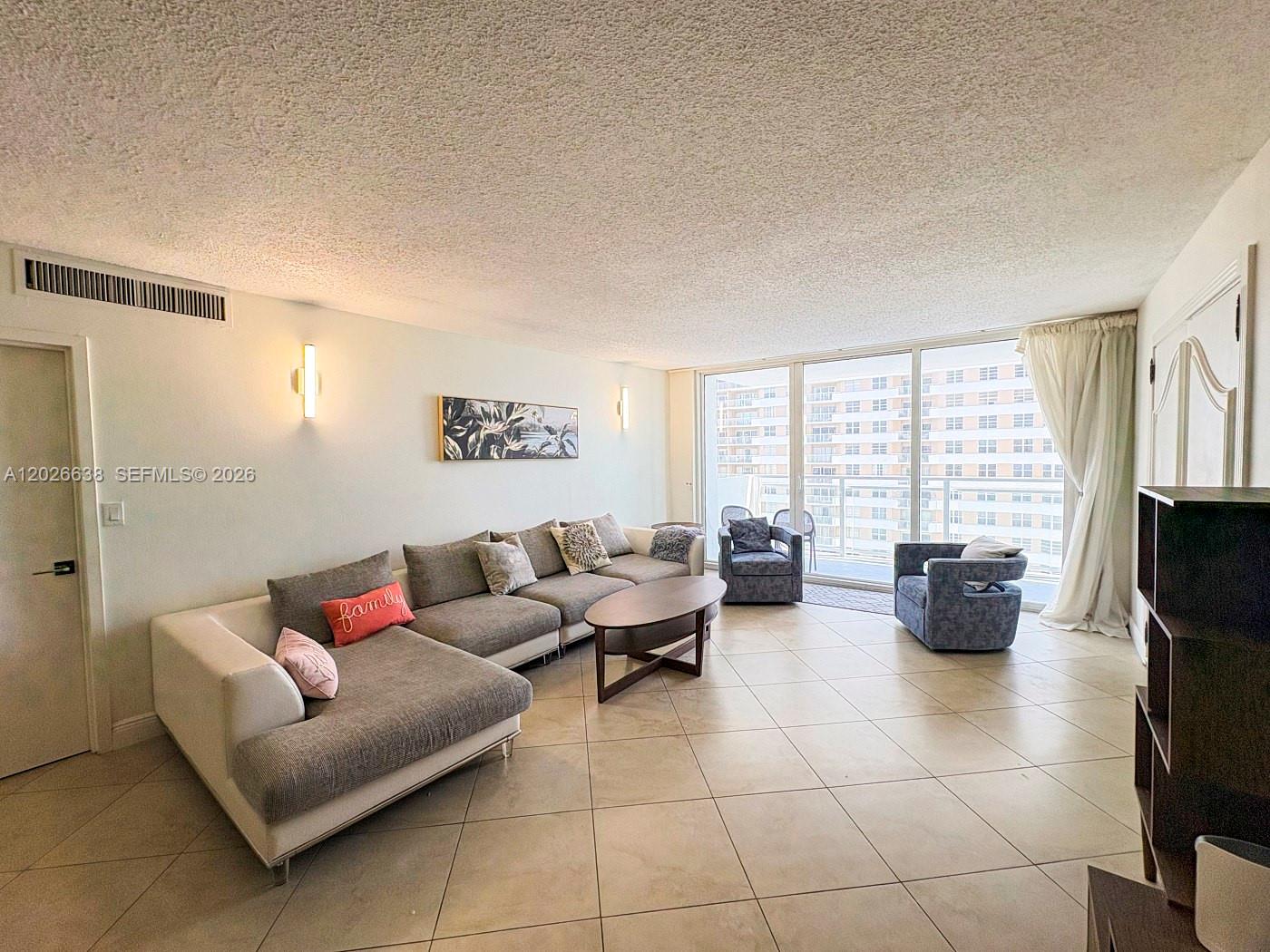 A living room features a large sectional sofa, tile flooring, and floor-to-ceiling windows — 2030 S Ocean Dr # 723, Hallandale Beach FL 33009, HALLANDALE BEACH, FL