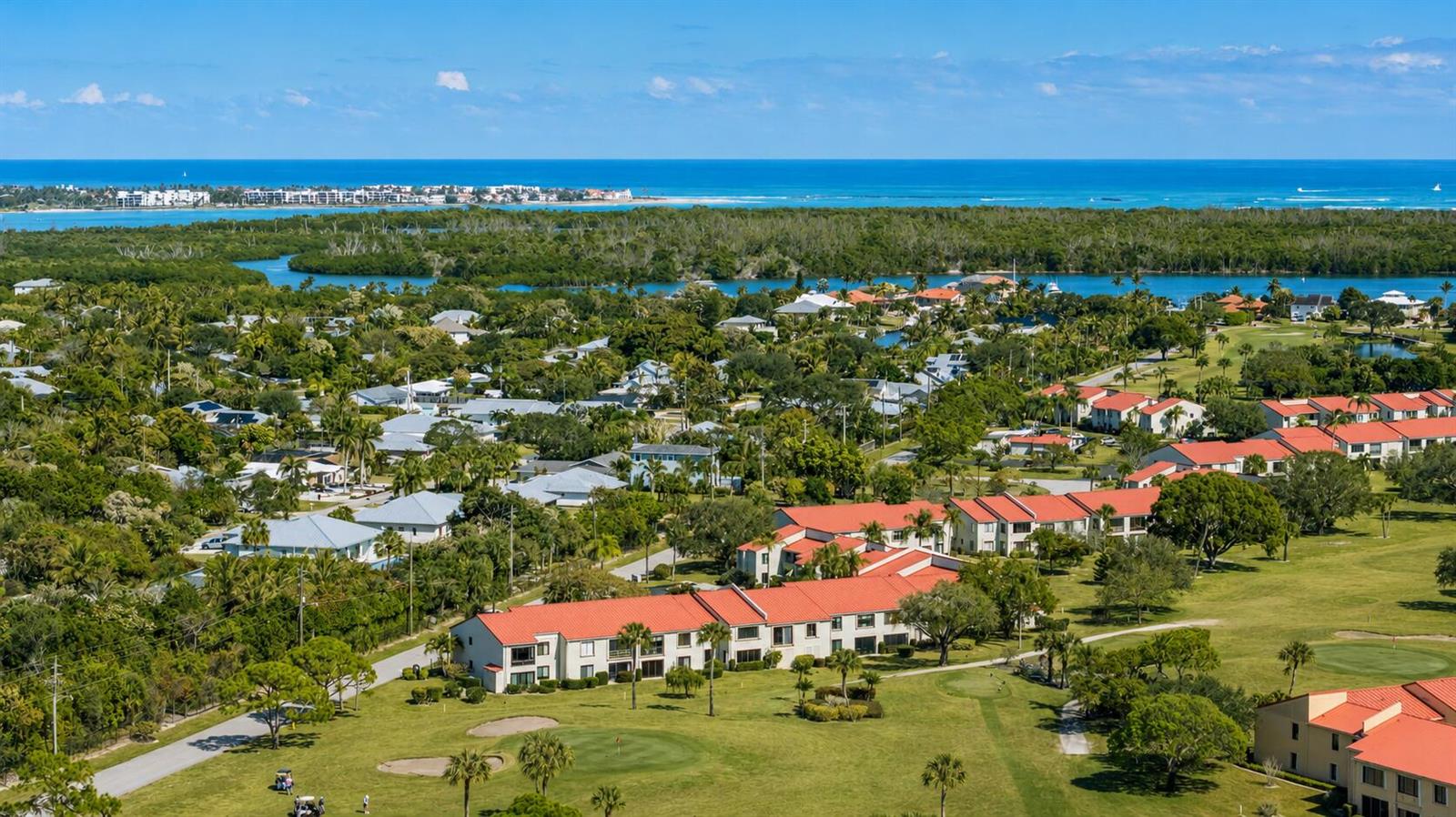 An aerial view shows a residential complex with red-tiled roofs surrounded by green golf courses — 5403 SE Miles Grant Road # 209, Stuart FL 34997, STUART, FL