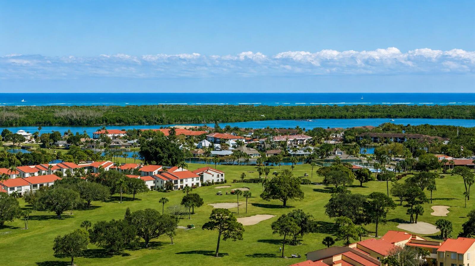 An aerial view of a golf course community with red-roofed buildings near a coastal waterway — 5403 SE Miles Grant Road # 209, Stuart FL 34997, STUART, FL