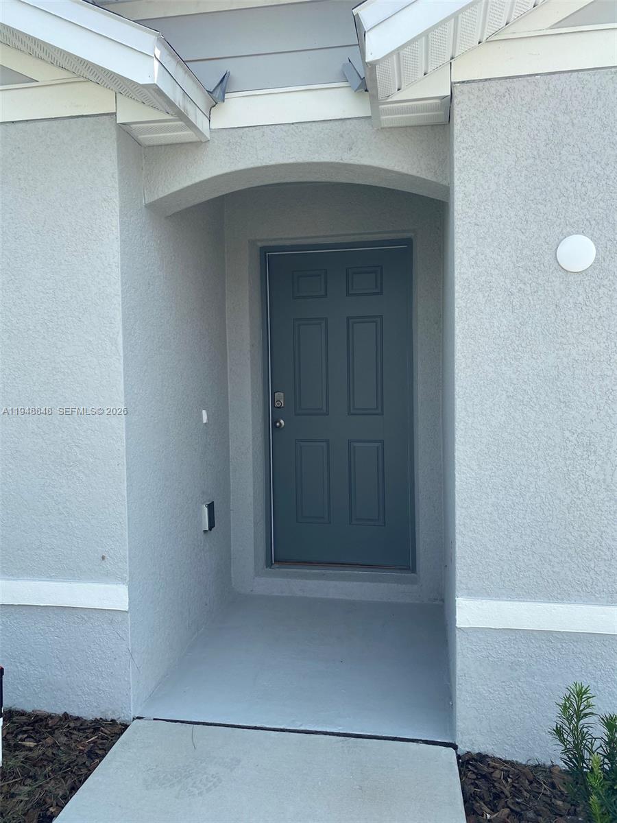 A gray front door is recessed within a light-colored stucco entryway — 8864 SW 49th CIRCLE, Ocala FL 34476, OCALA, FL