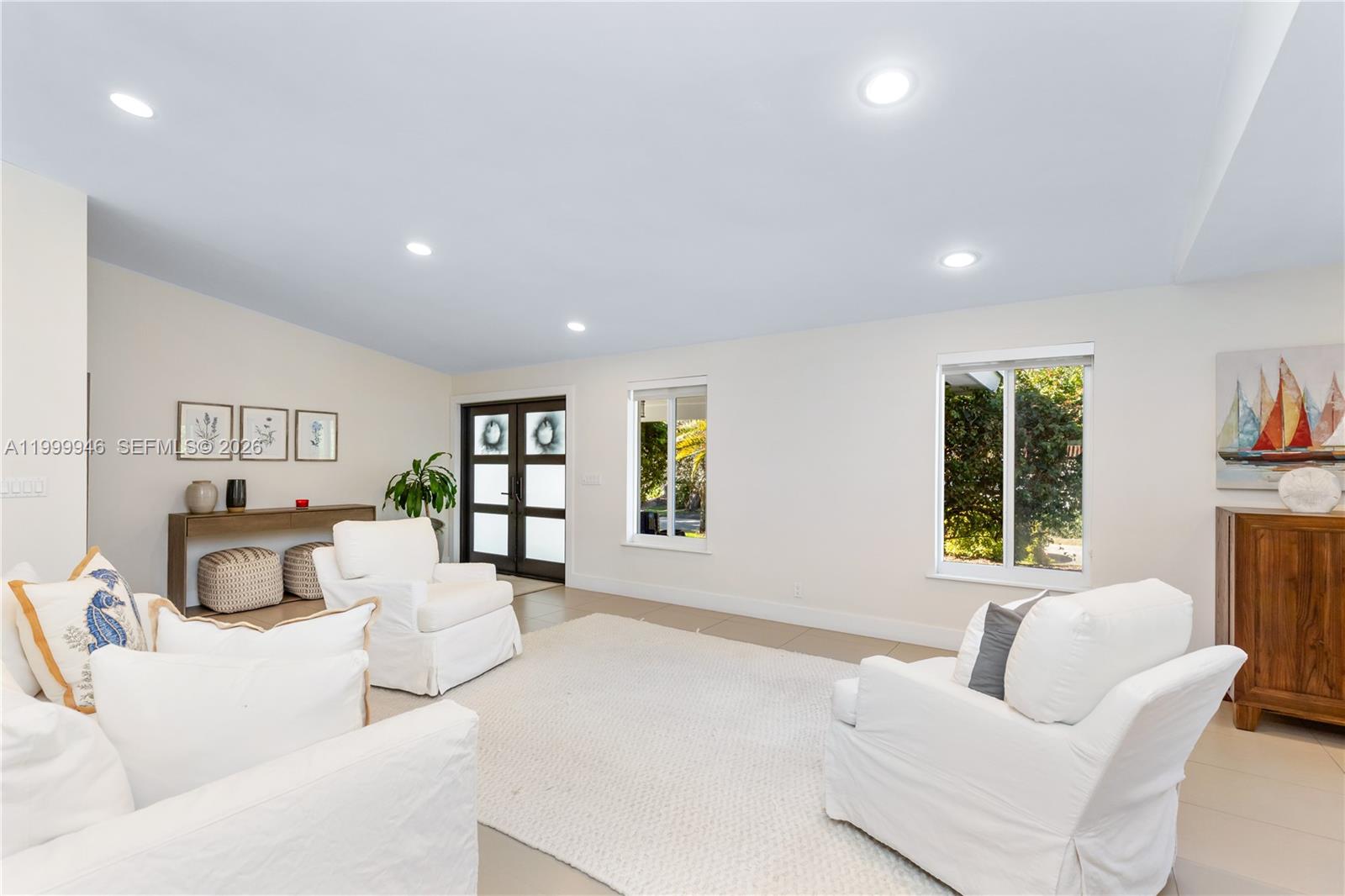 A bright living room features white slipcovered furniture, a large area rug, and double doors — 13303 SW 58th Ave, Pinecrest FL 33156, PINECREST, FL
