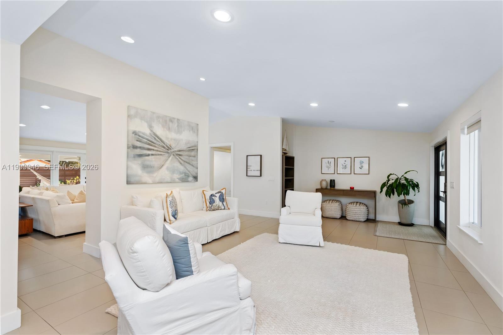 A bright living room features white furniture, tiled floors, and a large abstract wall painting — 13303 SW 58th Ave, Pinecrest FL 33156, PINECREST, FL