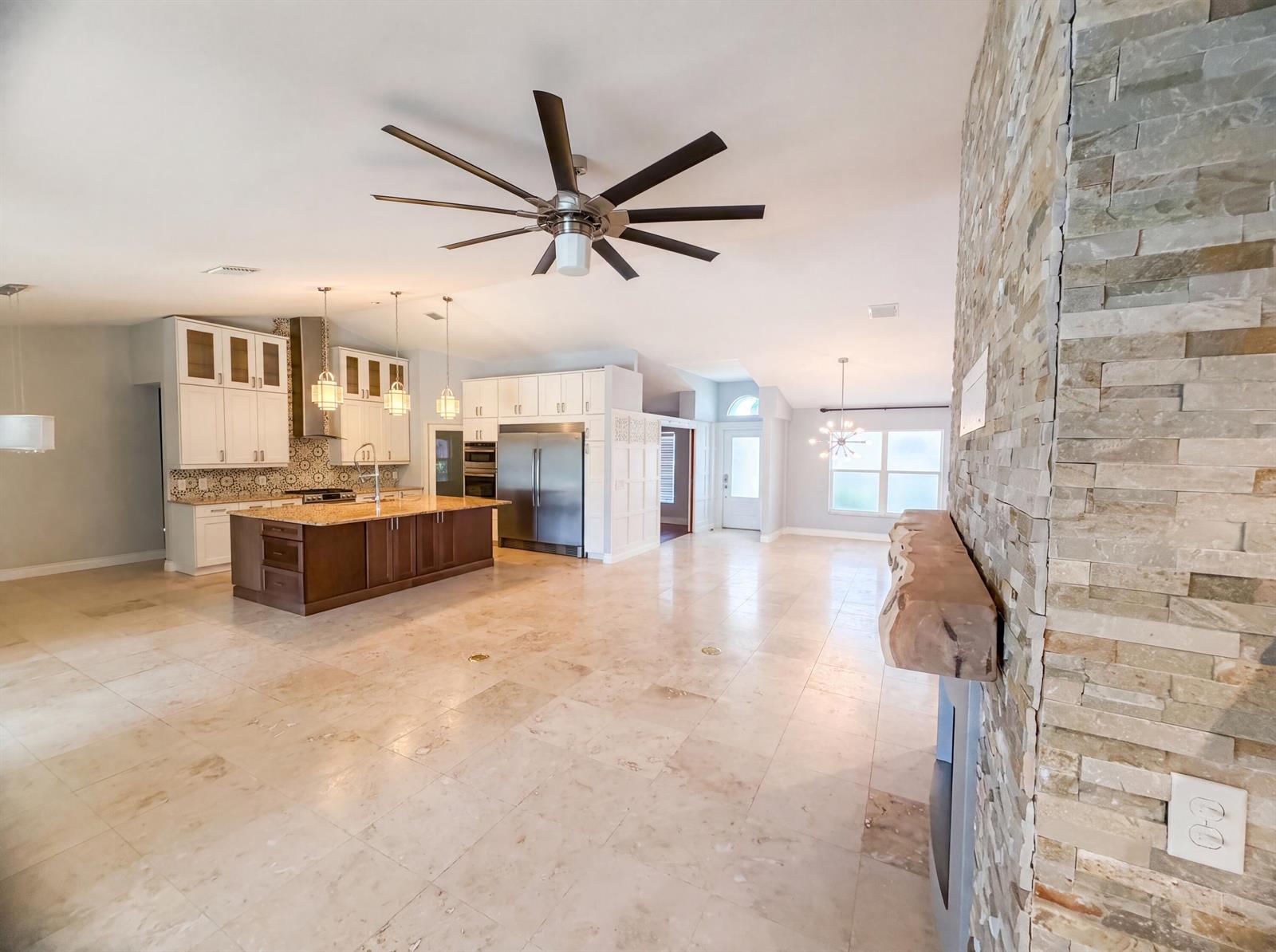 A spacious open-concept kitchen and living area featuring a stone fireplace and tile flooring — 2902 Serenity Circle S, Fort Pierce FL 34981, FORT PIERCE, FL
