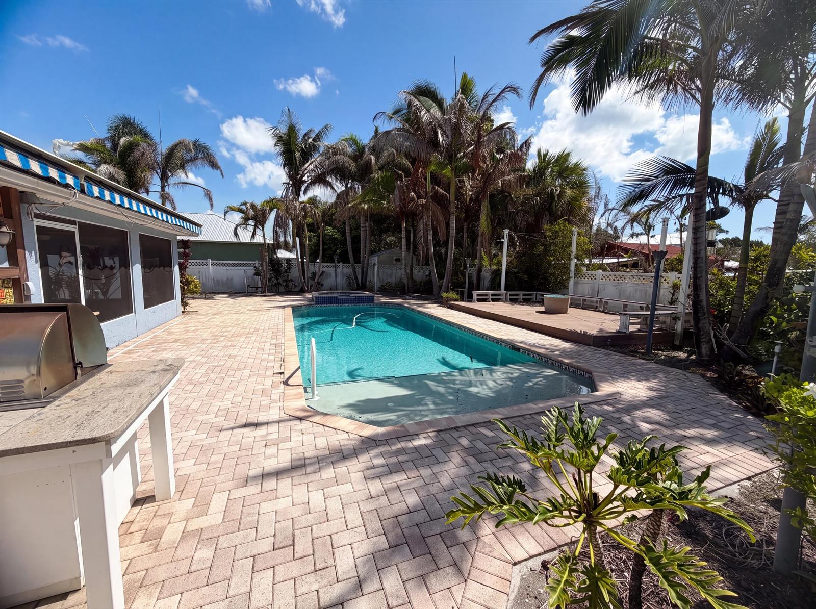 A backyard features a rectangular swimming pool, a brick paver patio, and several palm trees — 2902 Serenity Circle S, Fort Pierce FL 34981, FORT PIERCE, FL
