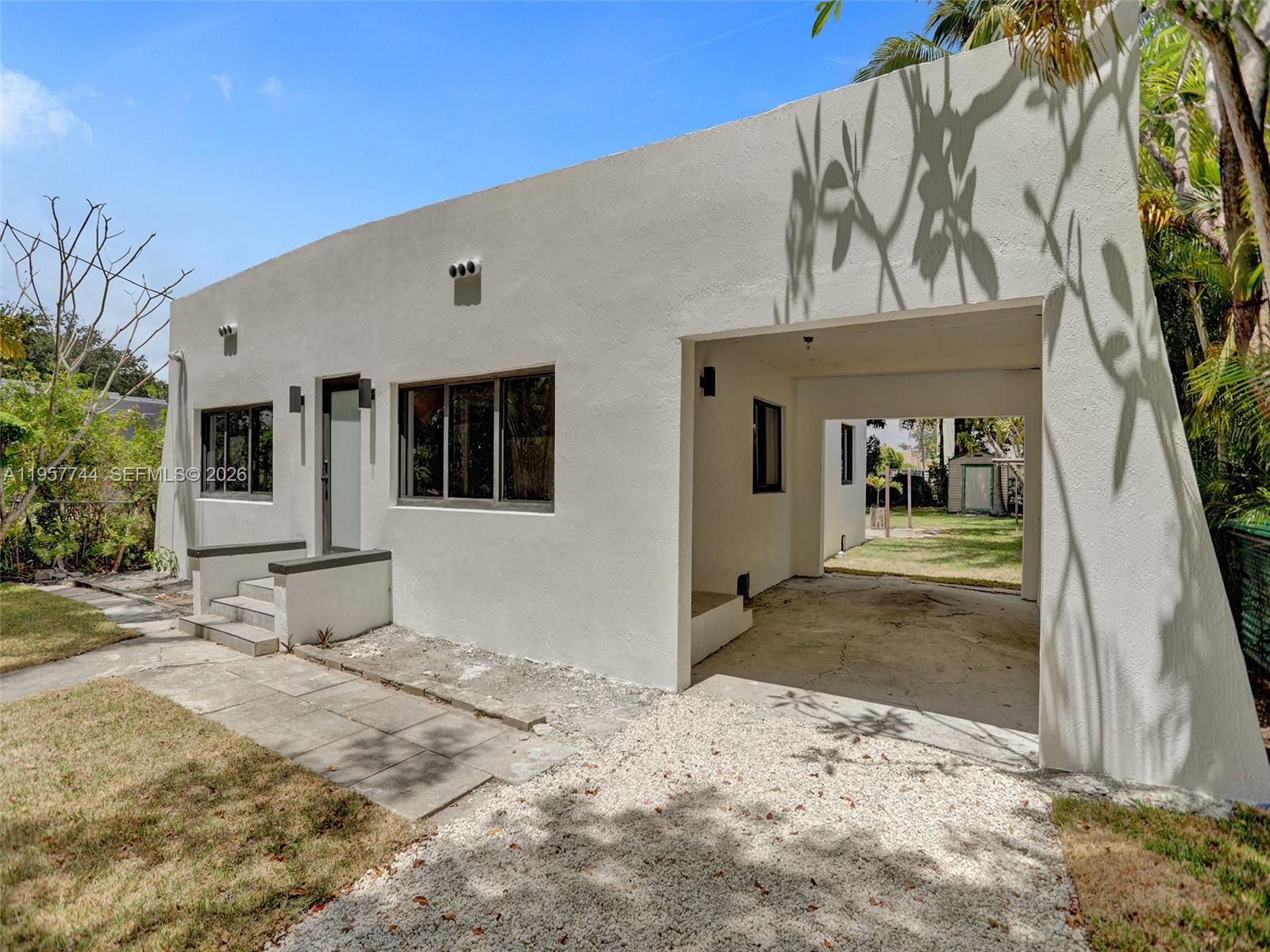 A white, single-story house features a front entrance, a carport, and a gravel driveway — 759 NE 127th St, North Miami FL 33161, NORTH MIAMI, FL