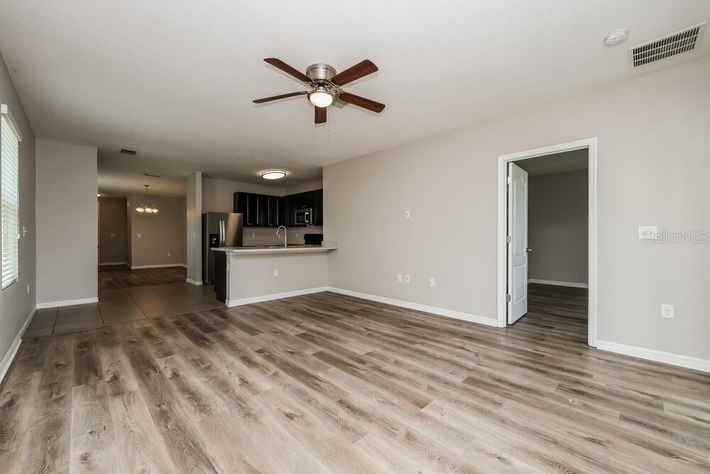An open-concept living area features wood-look flooring, a ceiling fan, and a kitchen with dark cabinets — 10540 WHISPERING HAMMOCK DRIVE, RIVERVIEW, FL