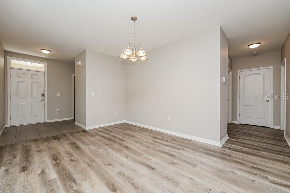 An empty dining area features light wood-look flooring, neutral walls, and a central chandelier — 10540 WHISPERING HAMMOCK DRIVE, RIVERVIEW, FL