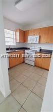 A kitchen features light wood cabinets, a white stove, and light-colored tile flooring — 4853 NW 9th Dr # 4853, Plantation FL 33317, PLANTATION, FL