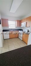 A kitchen features light wood cabinets, dark countertops, a white dishwasher, and a white stove — 4853 NW 9th Dr # 4853, Plantation FL 33317, PLANTATION, FL